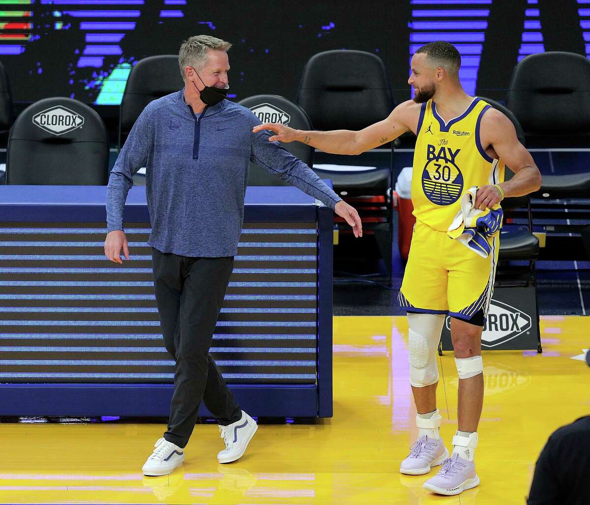 Stephen Curry (30) and head coach Steve Kerr share a smile after the Golden State Warriors defeated the Sacramento Kings 117-113 at Chase Center in San Francisco Calif., on Sunday, April 25, 2021.