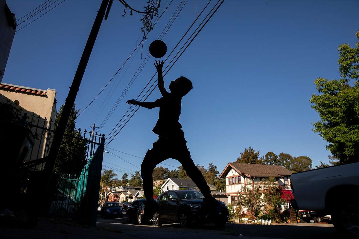 Angel Narvaez Cruz, 13, plays basketball outside his home along 25th Avenue in the Reservoir Hill neighborhood on Tuesday, May 4, 2021, in Oakland, Calif. His family has been living in the neighborhood for two decades.