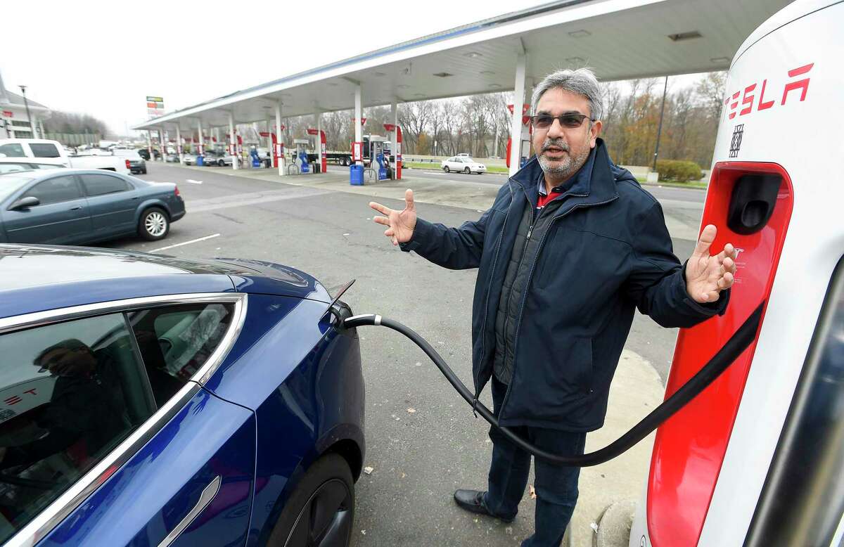 Ray Malkani, of Virginia, charges his Tesla vehicle at an Interstate 95 rest plaza on Nov. 27, 2019.