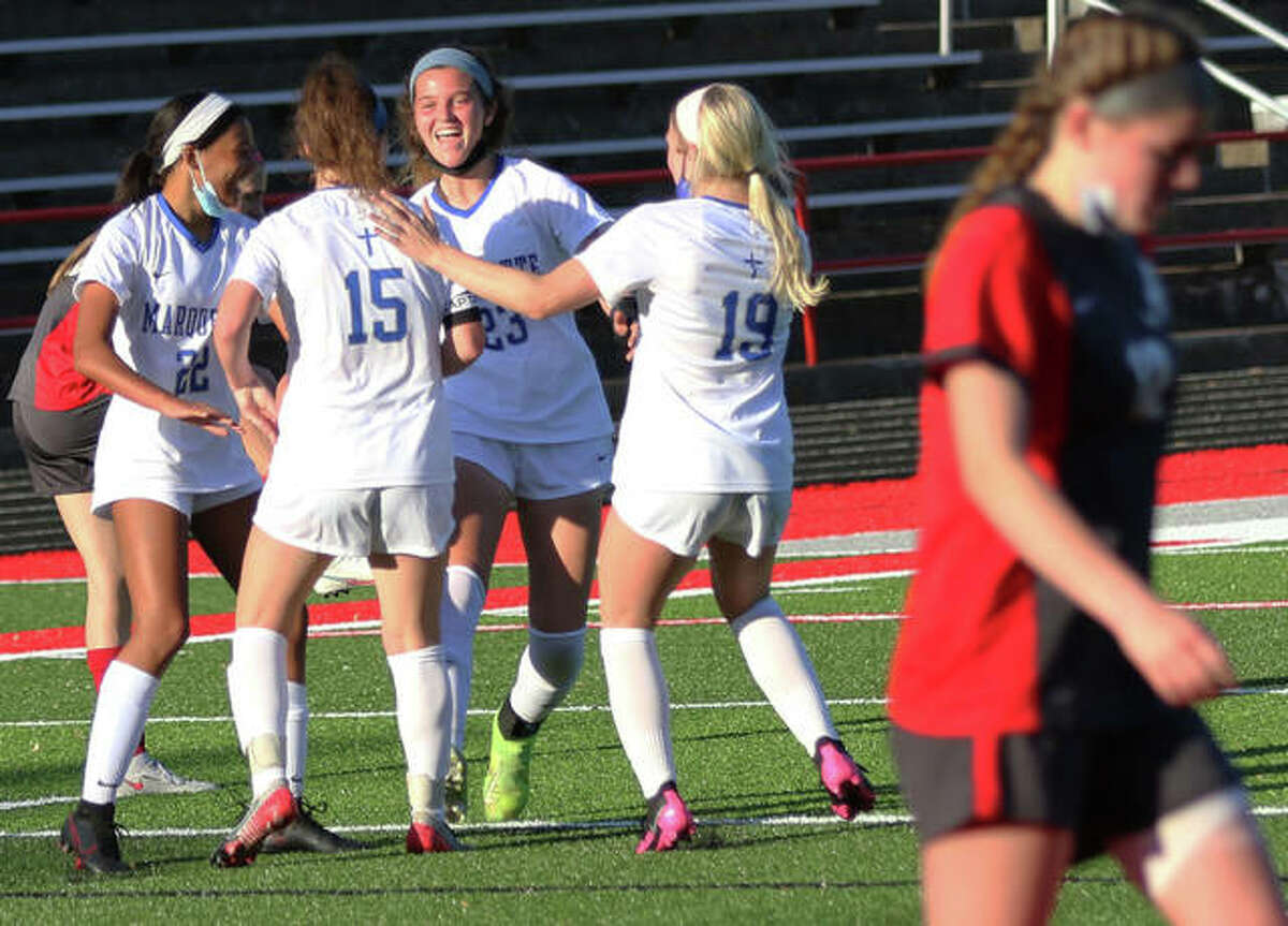 Marquette Catholic's Aela Scruggs (22), Madelyn Smith (15), Jillian Nelson (23) and Emma Anselm (19) celebrate Smith's first-half goal while Alton's Ainsley Redman walks toward the Redbird bench Wednesday at Public School Stadium in Alton.