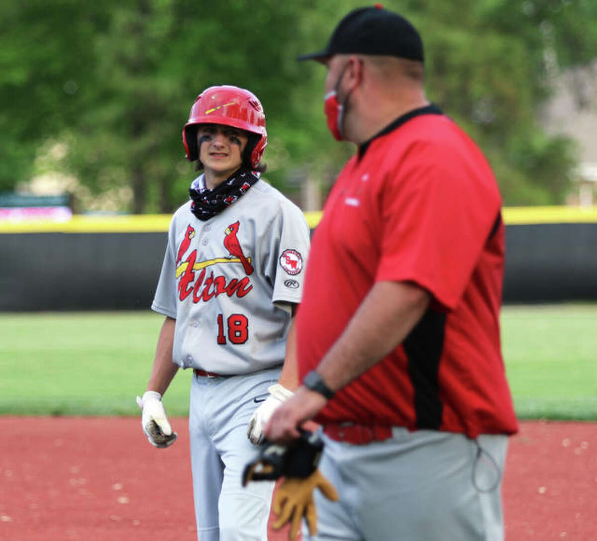 Alton’s James Vambaketes (left) looks to first base coach Brett Huff during Monday’s SWC loss in O’Fallon. Vambaketes had two hits and picked up a save in Wednesday’s rematch with the Panthers in Godfrey.
