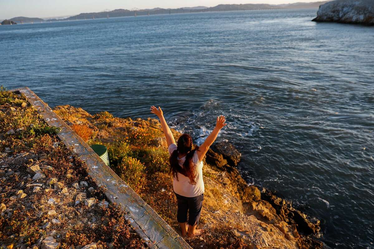 Innkeeper Desiree Heveroh momentarily raises her arms as she watches the sunset from the East Brother Light Station on May 3.