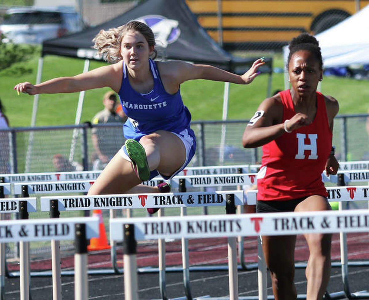 Marquette Catholic’s Tristan Fraley (left) clears a hurdle behind Highland’s Tanille Thompson during a 100-meters hurdles heat Wednesday at the Triad Invite in Troy.