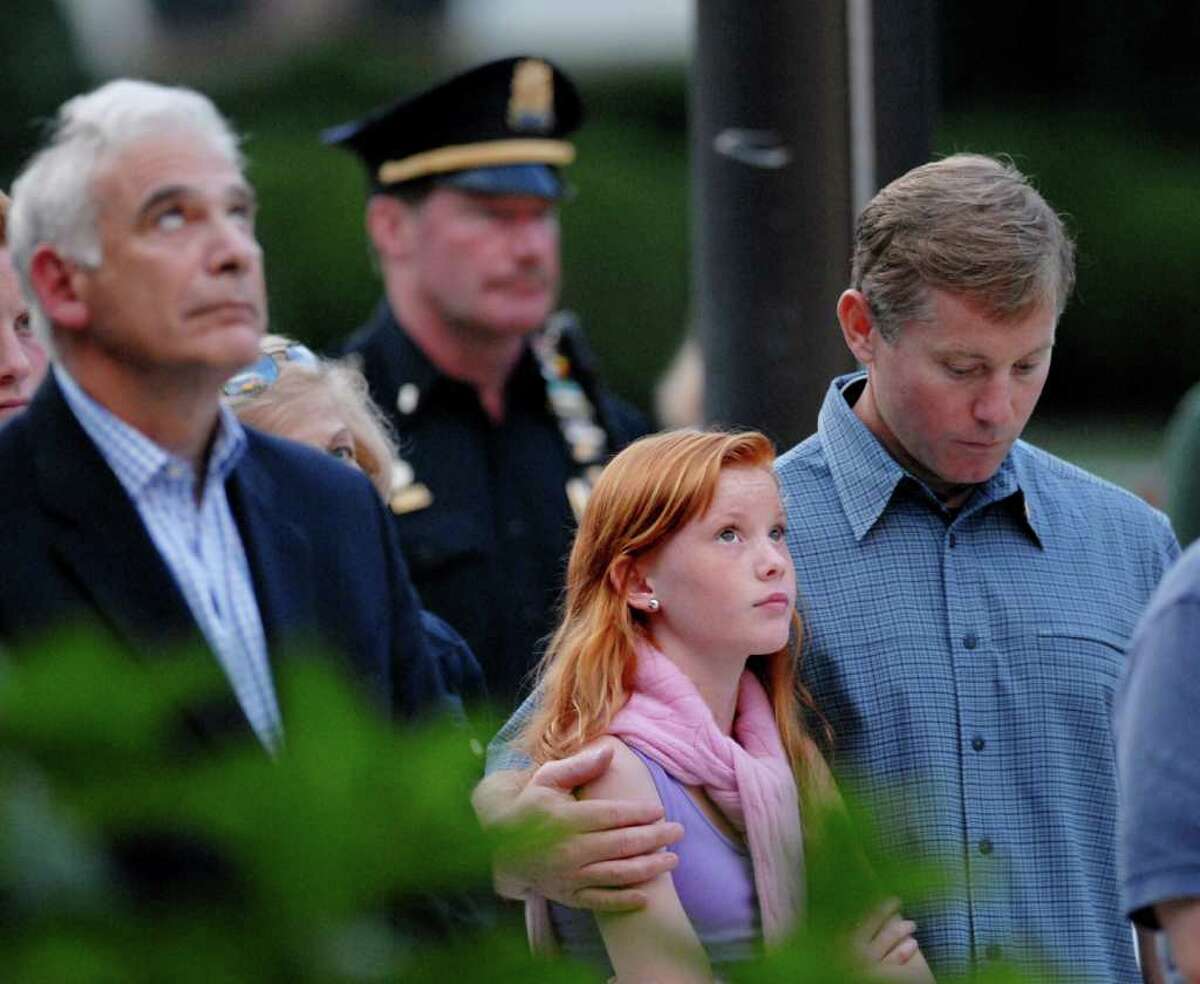 Rob Robben of Old Greenwich, at right with his head bowed, has his arm around his daughter, Mary Caroline Robben, 13, as she looks skyward during the 9/11 remembrance ceremony at Greenwich Town Hall, Saturday evening, Sept. 11, 2010.