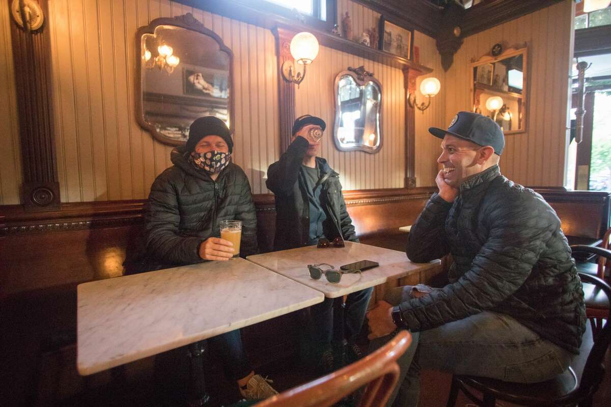 Left to right, Jeremiah Botchlet, Patrick Houck and Luke Roy hang out with beers inside Shotwell's Saloon in San Francisco on May 6, 2021. Patrons were able to drink indoors at a bar for the first time since the start of the COVID-19 shutdowns in March 2020.