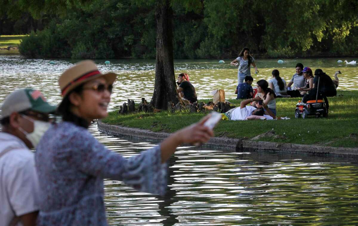 People relax by McGovern Lake on Thursday, May 6, 2021, at Hermann Park in Houston.