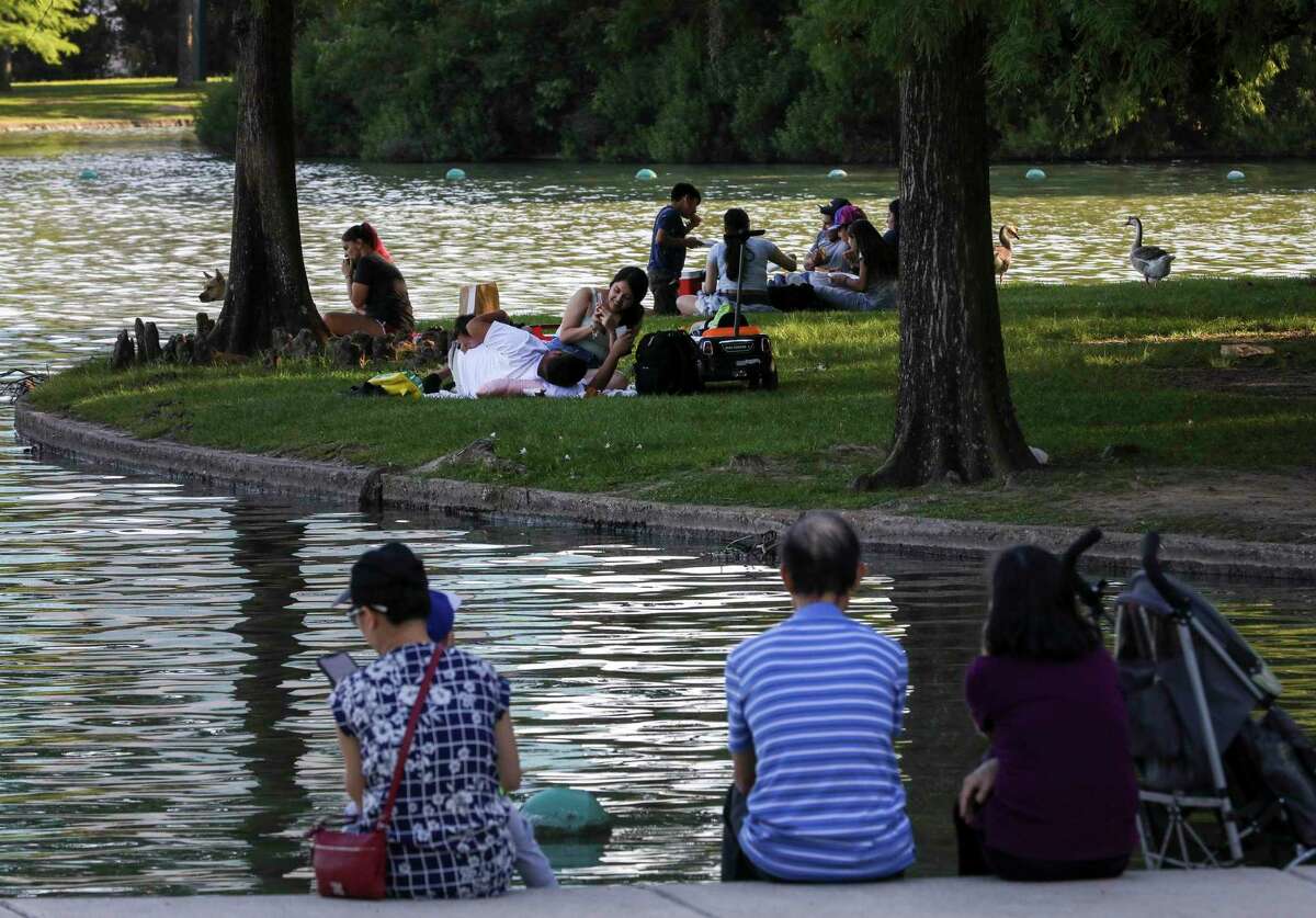 People relax by McGovern Lake on Thursday, May 6, 2021, at Hermann Park in Houston.