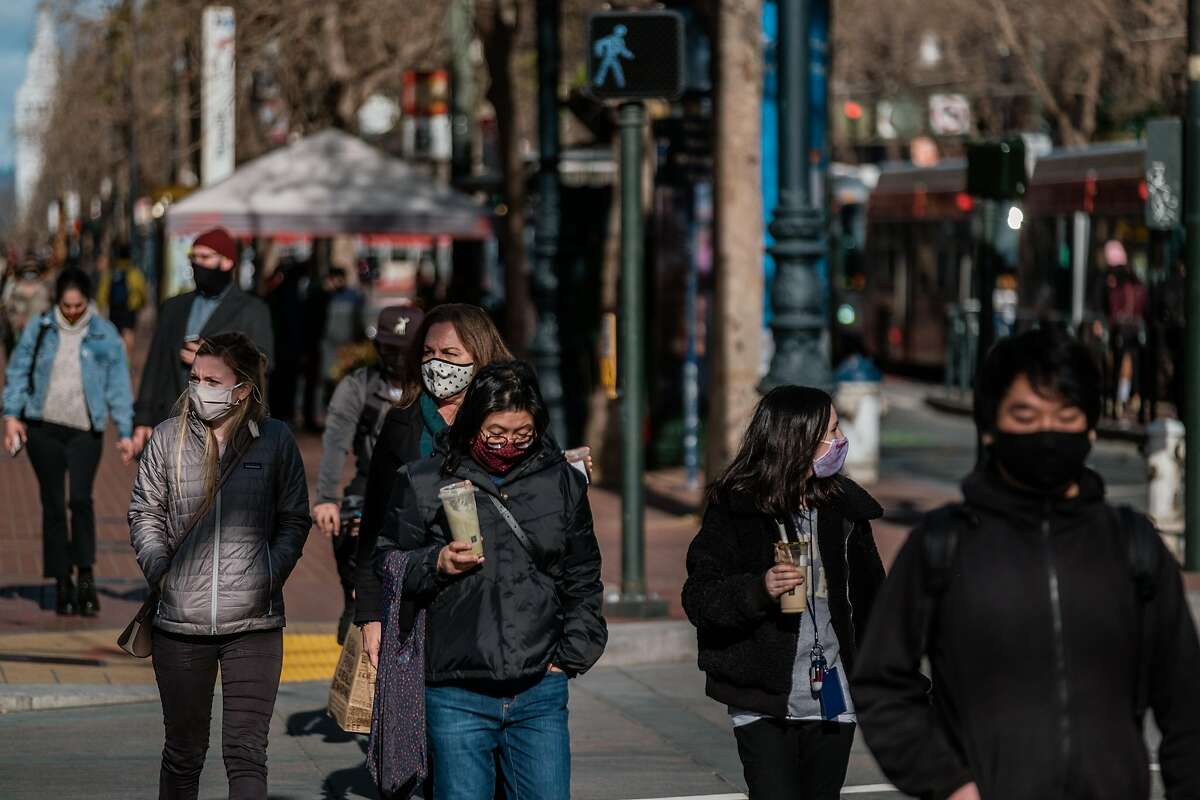 Pedestrians wearing face masks cross the street in San Francisco on Friday, February 12, 2021. The CDC recently said wearing double masks can help protect against the spread of COVID-19.
