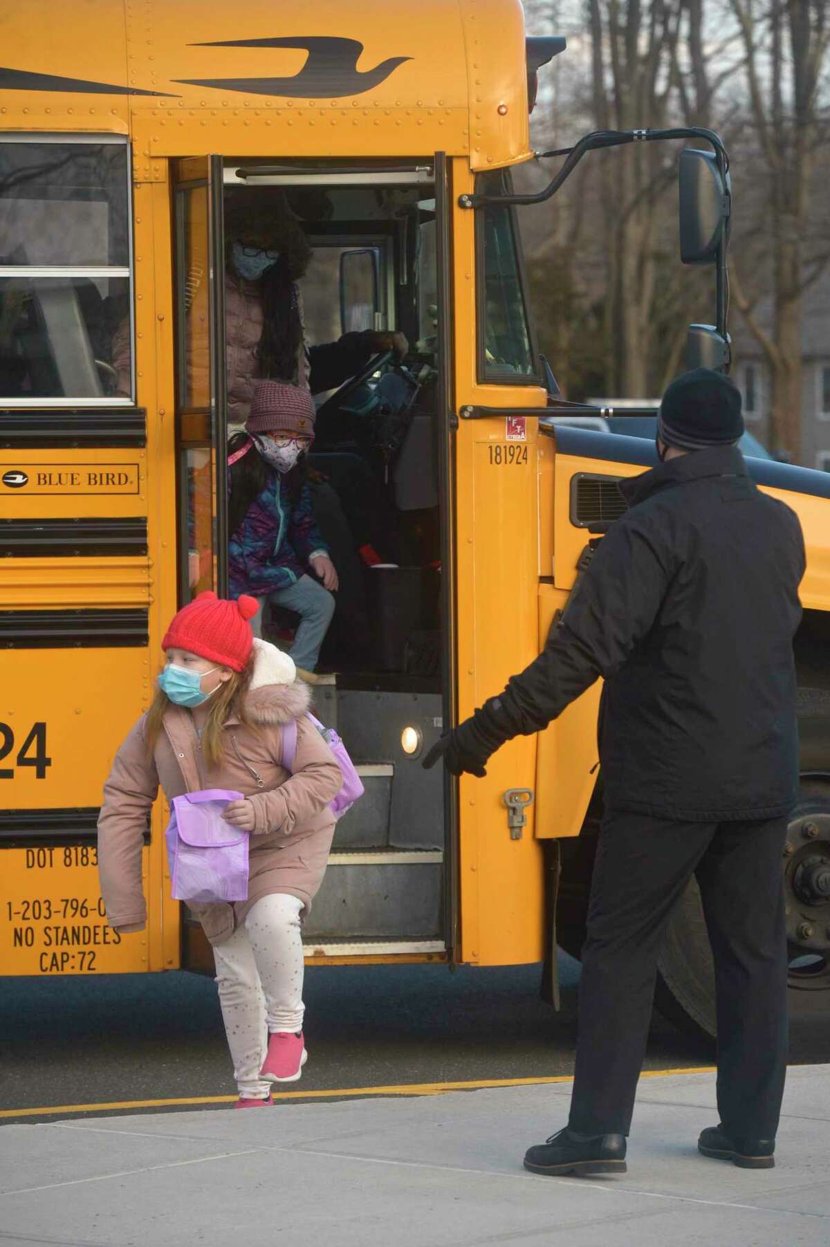 Stadley Rough Elementary School principal Lenny Cerlich welcomes students and their bus driver back to school for the first time since March of last year. Tuesday, January 19, 2021, in Danbury, Conn.