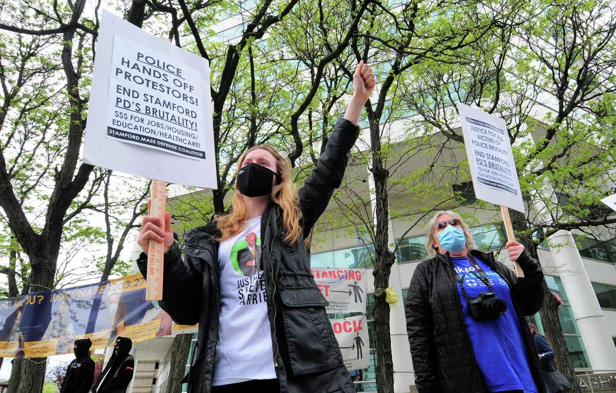 Kate Dempsey, of Darien, left, attends a protest organized by Stamford Mass Defense Coalition in front of the Stamford Government Center in downtown Stamford on Saturday. The rally was held to urge city and state officials to drop all charges against people arrested during march last summer and to protest the death of Stamford resident Steven Barrier.