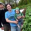 From left, Andy Macri photographed with his daughter, Andromeda Macri, and grandson, Augie Campbell, 8 months, alongside a row of rhubarb at River Crest Farm in Milford on May 5, 2021.