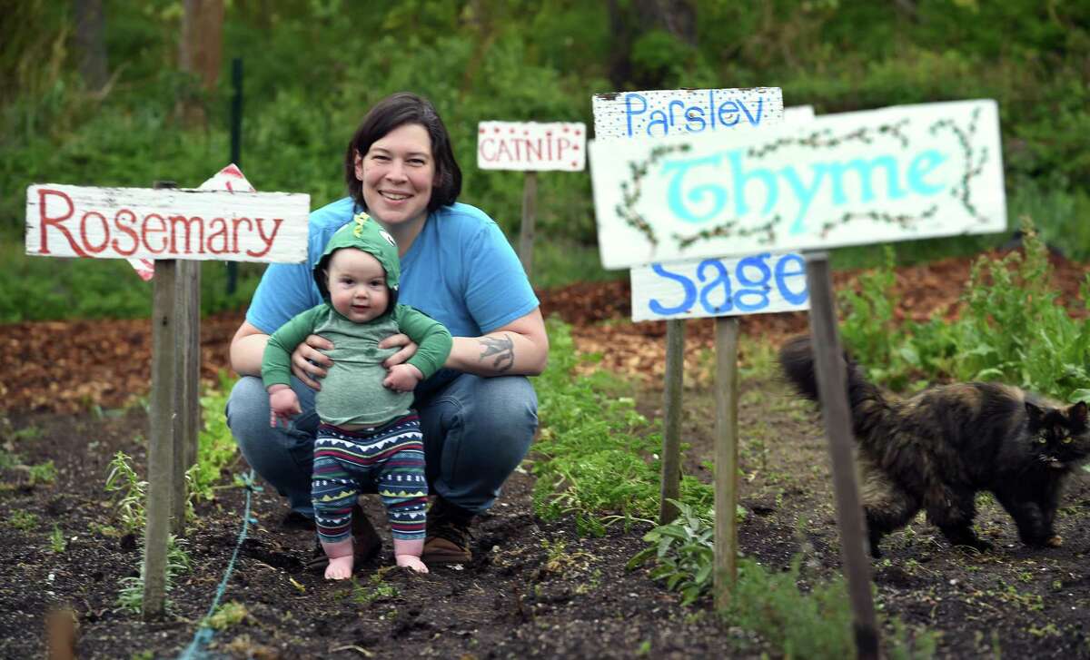 Andromeda Macri photographed with her grandson, Augie Campbell, 8 months, among rows of herbs at River Crest Farm in Milford on May 5, 2021.