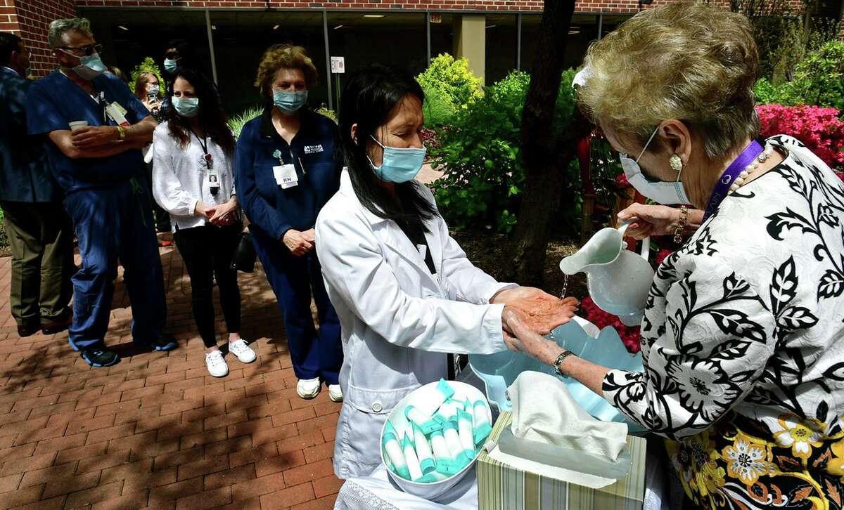 Clinical Coordinator for the Specialty Clinic, Ellen Aversa, receives the blessing of the hands by hospital chaplain Carol Bauer as Norwalk Hosptal staff gather for a dedication ceremony for the newly planted courtyard and the garden Friday, May 7, 2021, in Norwalk, Conn. The courtyard garden was dedicated to the hospital staff who worked during the height of the pandemic. Three new trees, 10 shrubs and 10 perrenial flowers were planted.