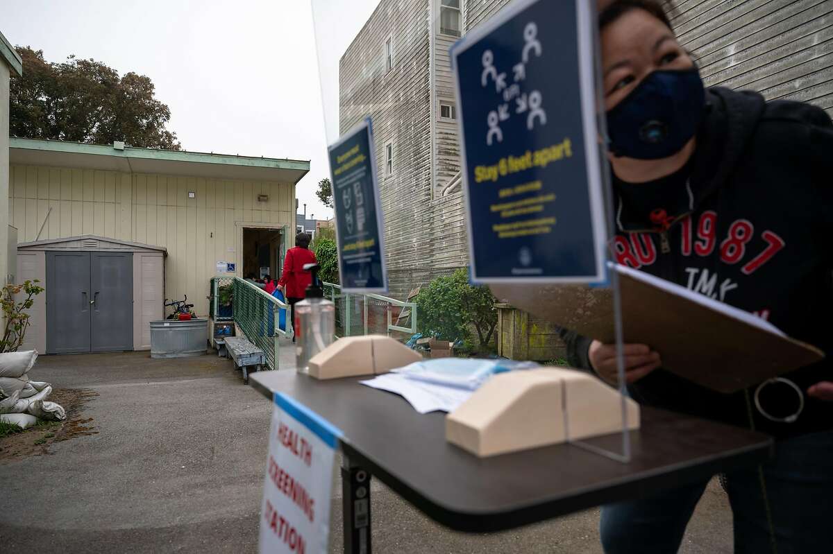 A staff member at Jefferson Early Education School in San Francisco screens and checks children in for their first day of school in April.