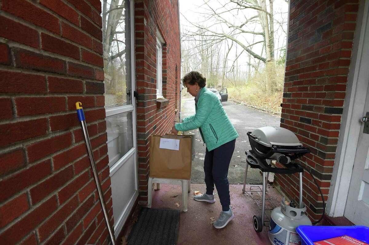 Eileen Westfahl of Stamford, one of many volunteers volunteering at SilverSource, carries bags of groceries to an elderly resident's home in the Springdale in 2020.