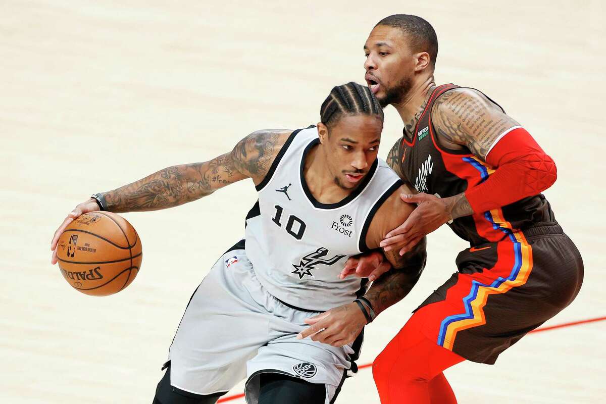 DeMar DeRozan of the Spurs dribbles against Damian Lillard of the Trail Blazers during the first quarter at Moda Center on May 8, 2021 in Portland, Ore.