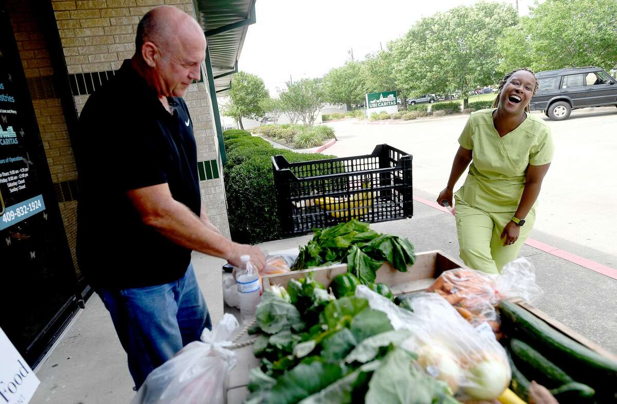 Tim Andrues with Slow Food Beaumont jokes with Yvonne Harrison as she selects produce during the group's monthly fresh produce market outside Ubi Caritas in South Park Monday. The market offers fresh fruits and vegetables for 50 cents a pound, most. of which is purchased from the Beaumont Farmer's Market. The group aims to help support local farmers while getting more fresh produce into underserved communities that fall under the umbrella of "food deserts." Photo made Monday, May 10, 2021 Kim Brent/The Enterprise