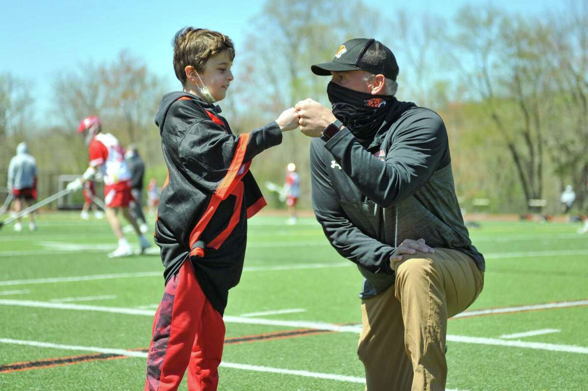 Conner Curran bumps fist with Ridgefield High School boys varsity lacrosse coach Roy Colsey, who surprised Curran with the opportunity to be honorary captain for the May 1 game.