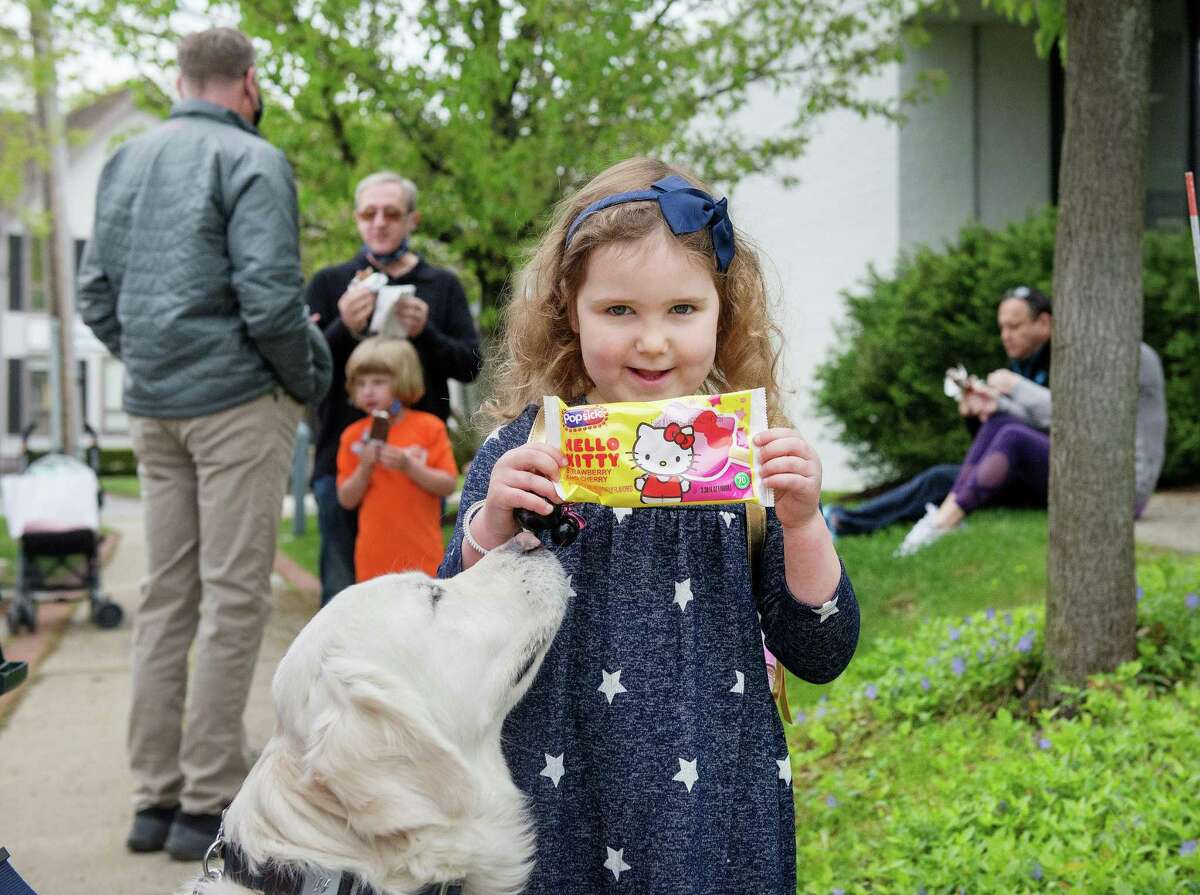 Dakota Kennedy, 4, and her dog, Harlow, of Wilton, receive ice cream from Jack Lewis of College Creamery at Wilton Library’s ice cream social on Saturday, May 8, 2021, in Wilton, Connecticut. New residents were invited to gather and receive individually wrapped ice cream bars courtesy of the library’s Board of Trustees. The social commemorates the library’s 125th anniversary.