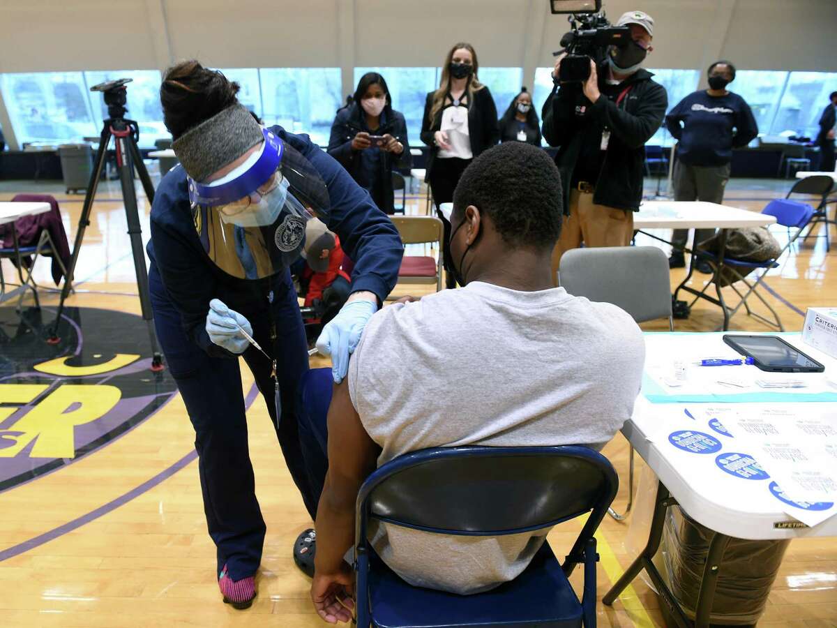 Gary Moore Jr., 16, receives his first dose of the Pfizer COVID-19 vaccine from New Haven City Health Department LPN Stephanie Rice at a COVID-19 vaccine clinic for people 16 and older at Hill Regional Career High School in New Haven on April 15, 2021.