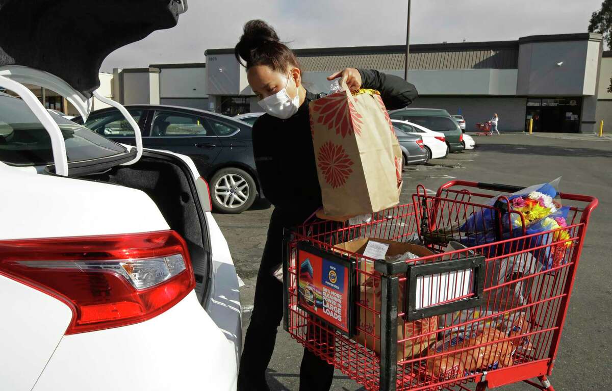 An Instacart worker loads groceries into her car for home delivery in San Leandro, Calif.