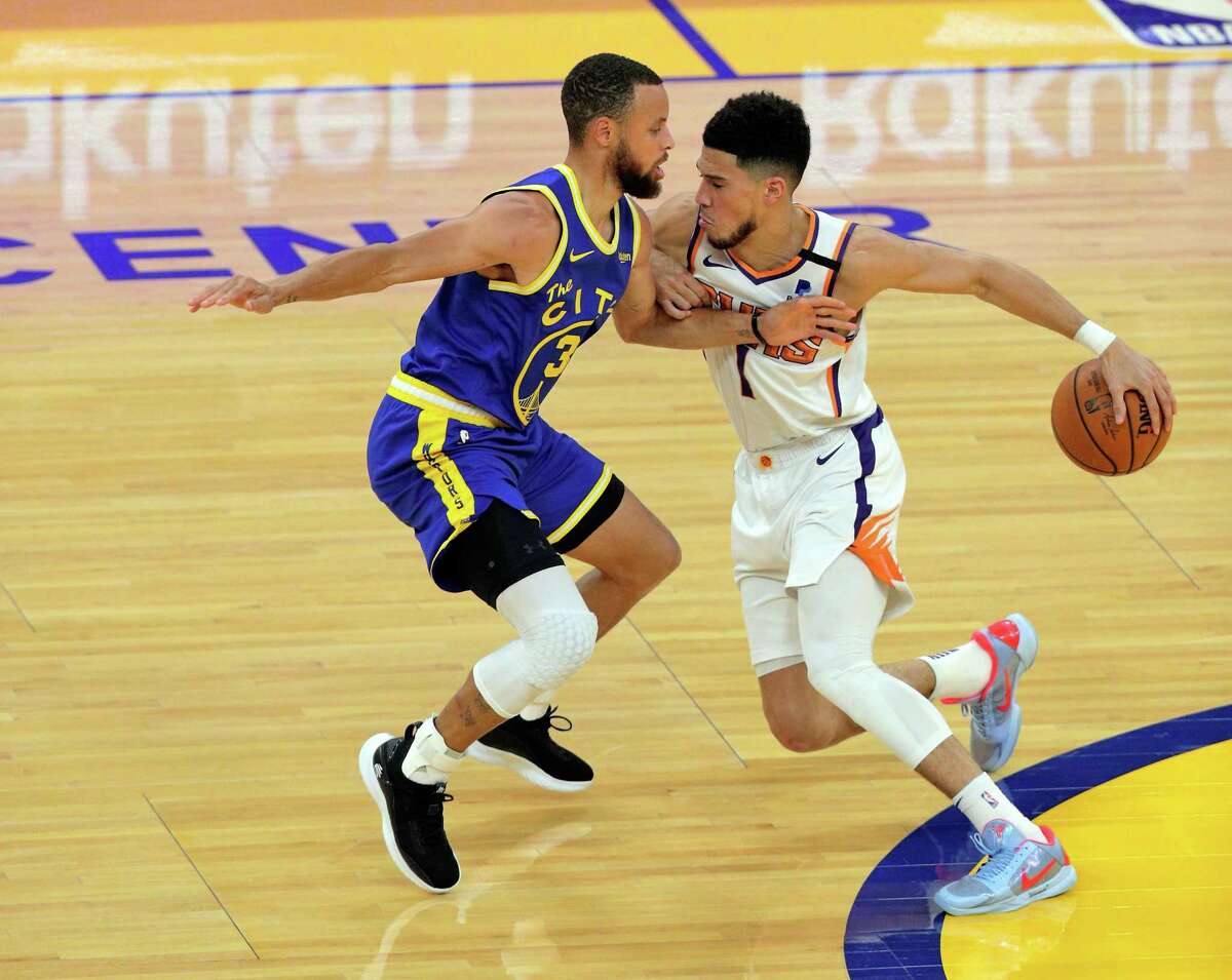 Stephen Curry (30) defends against Devin Booker (1) in the first half as the Golden State Warriors played the Phoenix Suns at Chase Center in San Francisco, Calif., on Tuesday, May 11, 2021.