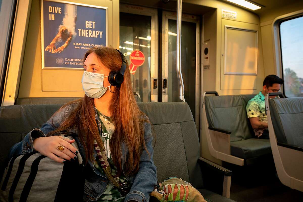 Chloe Pine wears a mask and social distances from other passengers while taking the BART (Bay Area Rapid Transit) from San Francisco towards Antioch to see her Aunt. Oakland, California. April 1, 2021. As COVID-19 cases drop and San Francisco enters the orange tier, the citywide mask mandate remains requiring all passengers wear masks and social distance on public transportation.d