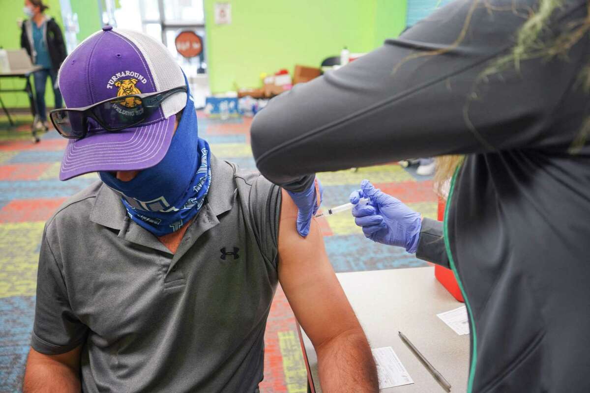 (FILES) In this file photo taken on April 30, 2021, healthcare worker vaccinates a man with the Covid-19 vaccine as the Pasadena Public Library hosts a mobile vaccine clinic set up by the Harris County Public Health, in Pasadena, Texas. - It's official: America's Covid-19 immunization campaign is stalling. While vaccination programs are lagging badly in many countries -- if they've begun at all -- mass vaccine sites across the US are closing due to dwindling demand, leaving the authorities exploring new ways to reach people who haven't yet gotten a shot. In Texas, as in much of the country, vaccinations are in freefall. A huge federal site in Arlington, between Dallas and Fort Worth, shut its doors in mid-April because of insufficient numbers. (Photo by Cécile CLOCHERET / AFP) (Photo by CECILE CLOCHERET/AFP via Getty Images)