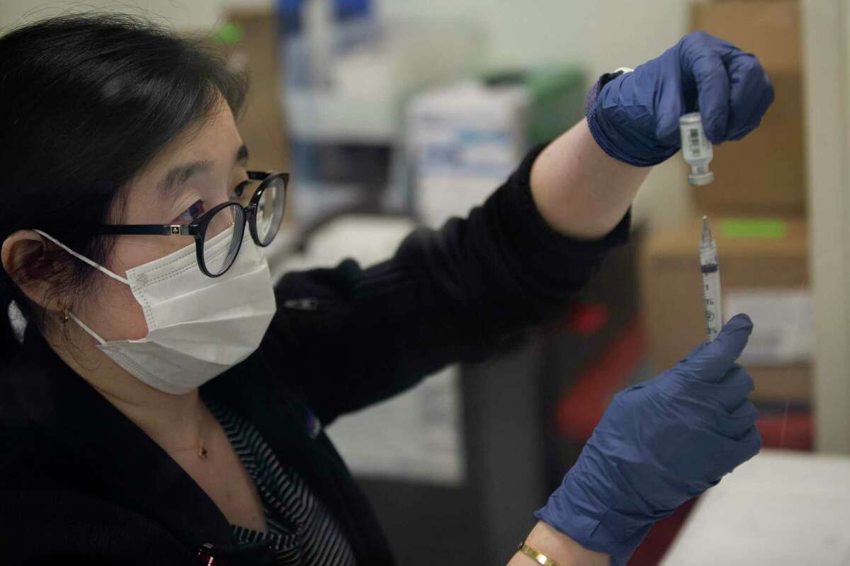 A registered nurse at San Francisco General Hospital, prepares Pfizer vaccines in April. The hospital began offering mRNA shots this week to people who originally got the Johnson & Johnson vaccine.