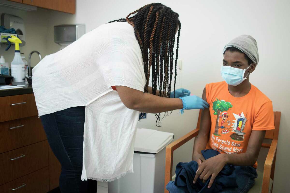 Registered nurse Ellena Steward-Scott administers a dose of the Pfizer vaccine to her son, Collin, 13, who was among the first teens to get the vaccine in the area.