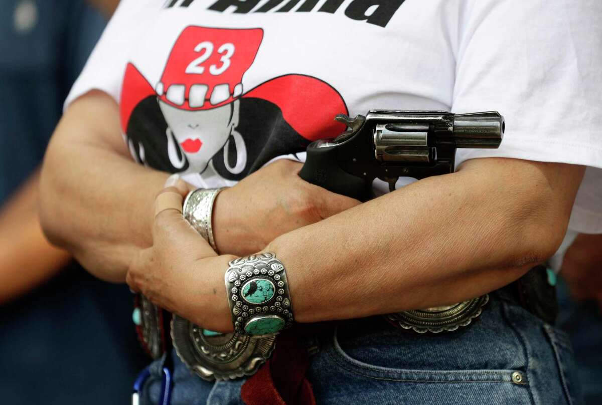 Dr. Alma Arredondo-Lynch holds a pistol as gun rights advocates gather outside the Texas Capitol where Texas Gov. Greg Abbott held a round table discussion, Thursday, Aug. 22, 2019, in Austin, Texas. (AP Photo/Eric Gay)