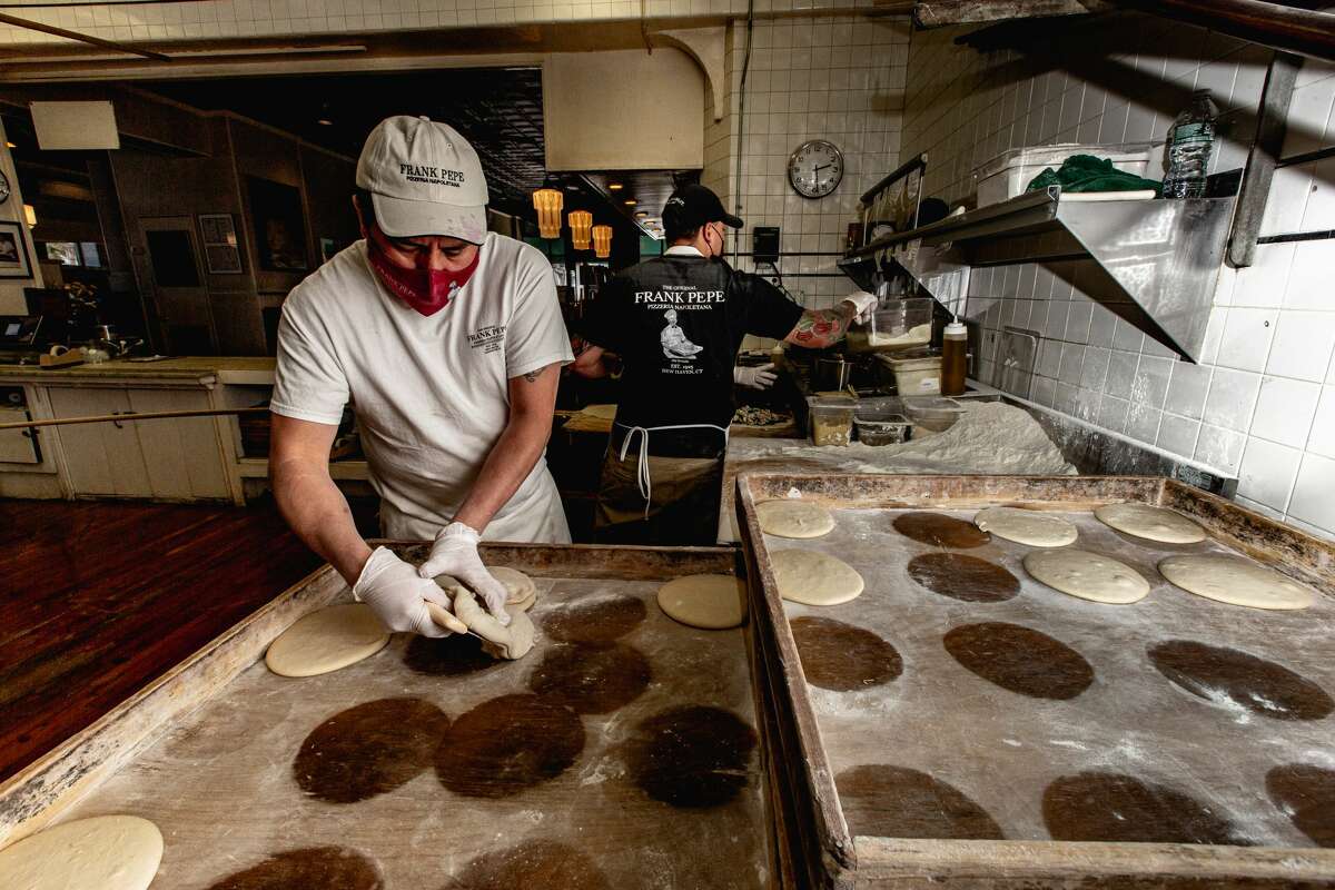 A pizza maker picks up fresh pizza dough at Frank Pepe's on April 23, 2021.
