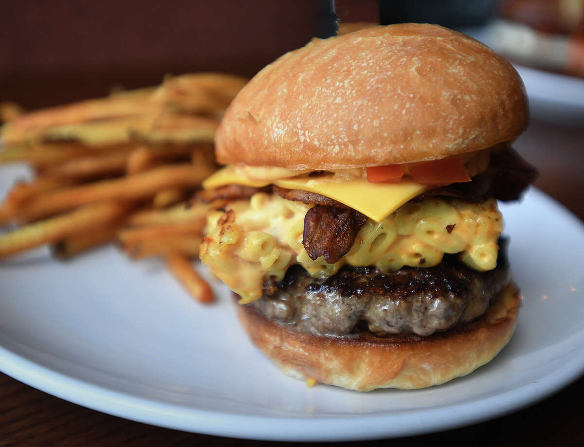 The Mac & Cheese Burger at Flipside Burgers & Bar features mac & cheese, bacon, cheese sauce, and pico de gallo toppings.