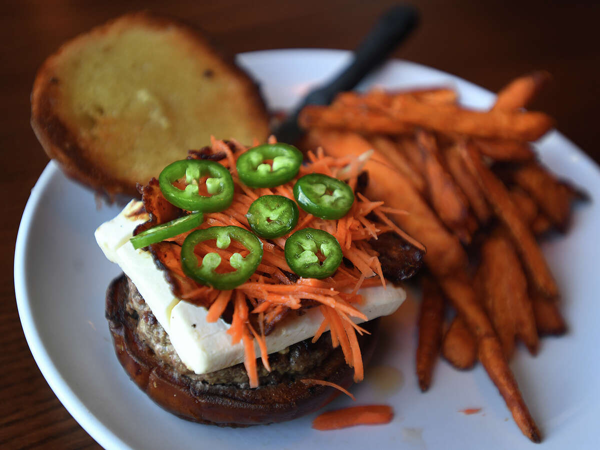 The Candy Popper Burger at Flipside Burgers & Bar features cream cheese, candied bacon, candied jalapenos, sweet carrots, and honey toppings with a pretzel bun.