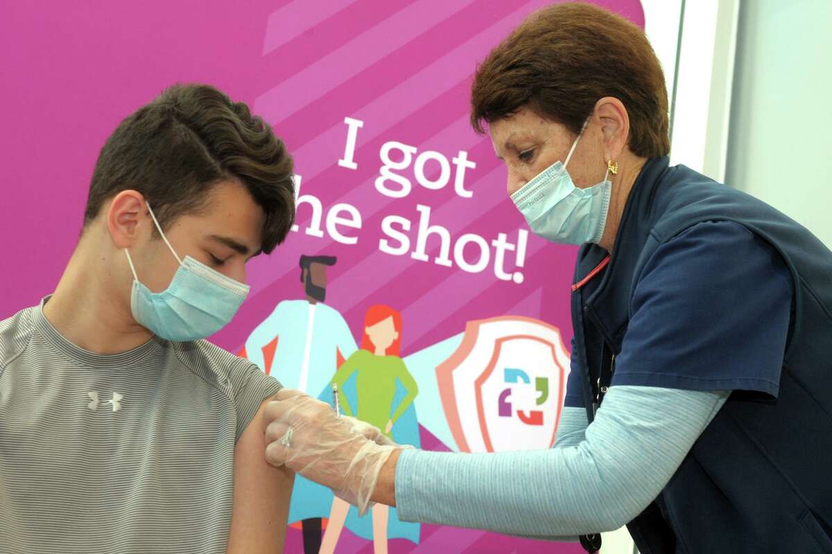 13-year old Matthew Loiz, of Shelton, gets a band aid after receiving a COVID-19 vaccination shot from nurse Mo Blees at the mass vaccination clinic on Sacred Heart University’s West Campus, in Fairfield, Conn. May 13, 2021.