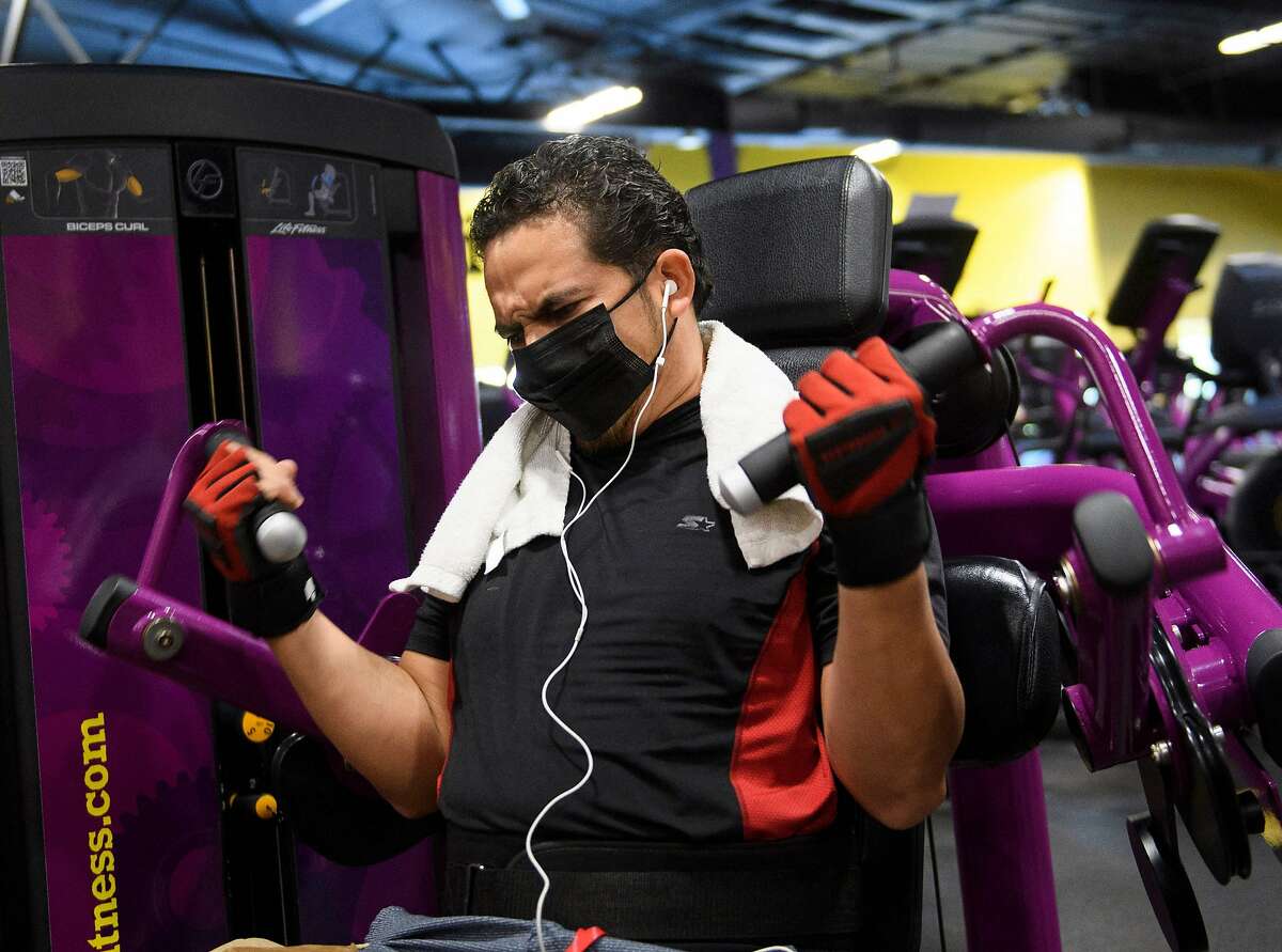(FILES) In this file photo taken on March 16, 2021, a customer wears a face mask inside a Planet Fitness Inc. gym as the location reopens after being closed due to the Covid-19 pandemic in Inglewood, California. - Covid cases are declining quickly while vaccinations continue to rise slowly but surely in the US, the former epicenter of the pandemic. Many experts believe the time will soon be right for the federal government to ease its recommendations on indoor masking across the board, and say doing so could help encourage more vaccine holdouts about the clear benefits of getting their shots. (Photo by Patrick T. FALLON / AFP) (Photo by PATRICK T. FALLON/AFP via Getty Images)