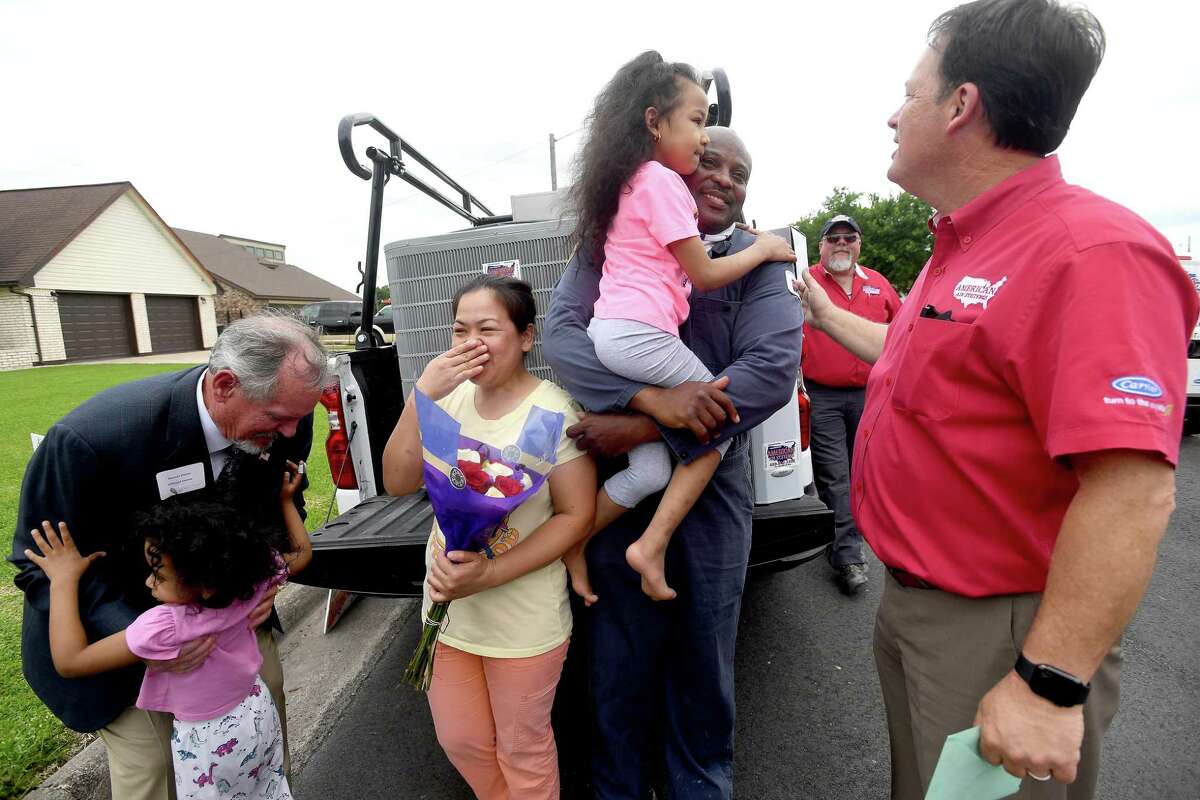 Vernon Pierce picks up Diane Ware as Susie and Henry Ware, holding daughter Valerie, are suprised by American Air owner Lee Potter and a large group with a brand new Carrier air conditioning system at their home in Port Arthur Thursday. The family have been without air conditioning since their home was destroyed in Harvey and have suffered numerous other tragedies since. They were selected as this year's recipients of American Air's third annual give-away to a family in need. Photo made Thursday, May 13, 2021 Kim Brent/The Enterprise