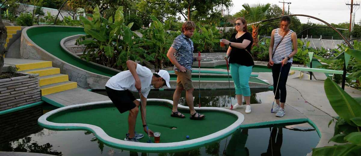 John Martinez, from left, Noah Bierwith, Anna Van Buskirk and Cassie Debolt play miniature golf at a UT Health Sciences Center party at Cool Crest Miniature Golf.