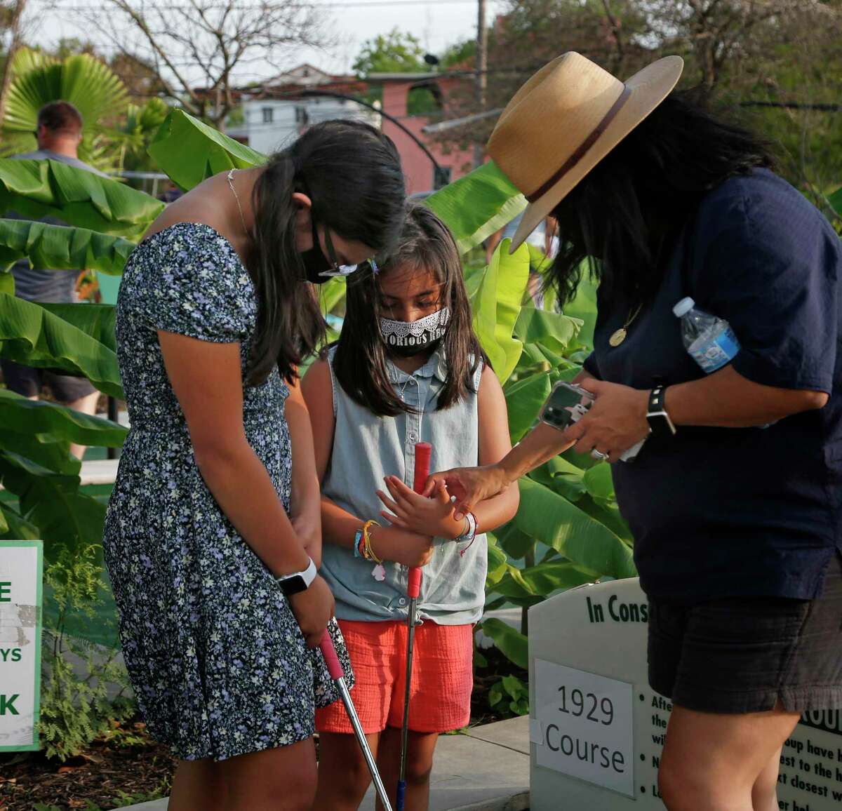 Martha Martinez-Flores helps her daughters 14-year-old Mara Flores and 8-year-old Mia Flores figure out the proper way to hold a putter during a recent visit to Cool Crest Miniature Golf.