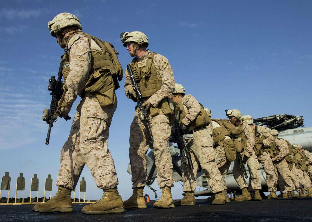 U.S. Marines pivot into position during an exercise on the flight deck of the amphibious transport dock ship USS San Antonio in 2013.