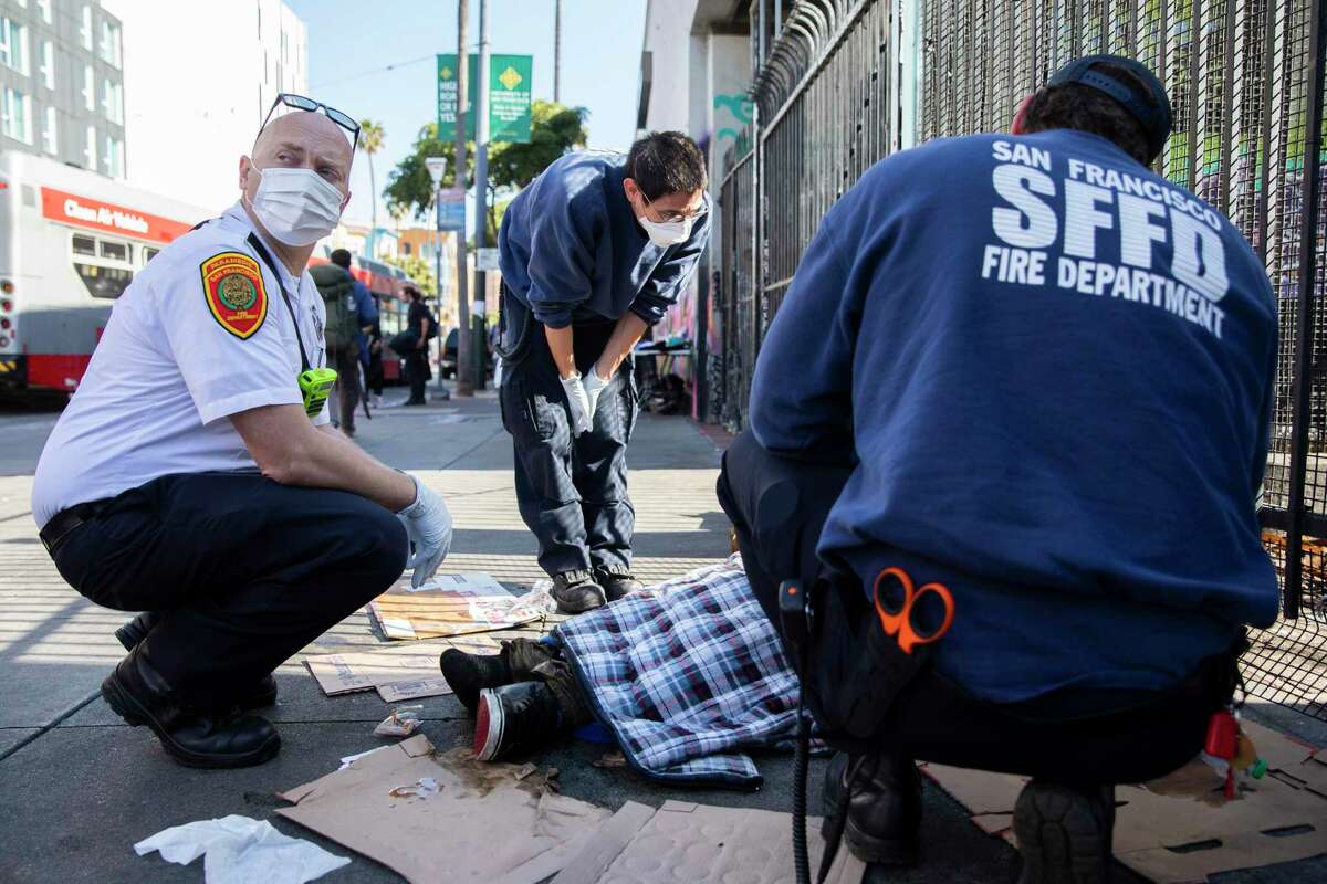 旧金山护理人员艾迪鸟(左)连接两个紧急医疗技术人员在评估一个无家可归的人在附近遇险16和使命的街道。