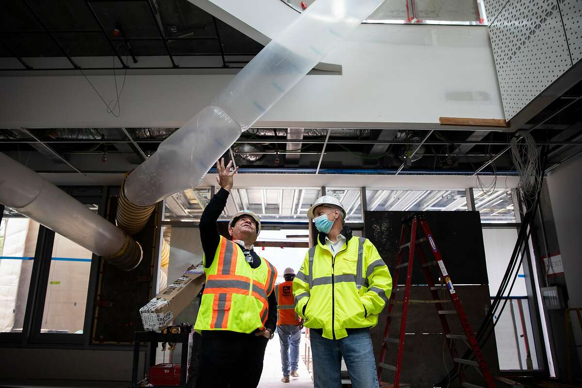 John Pritzker (left) and construction lead Doug Byles look up at the atrium of the future psychiatry building.
