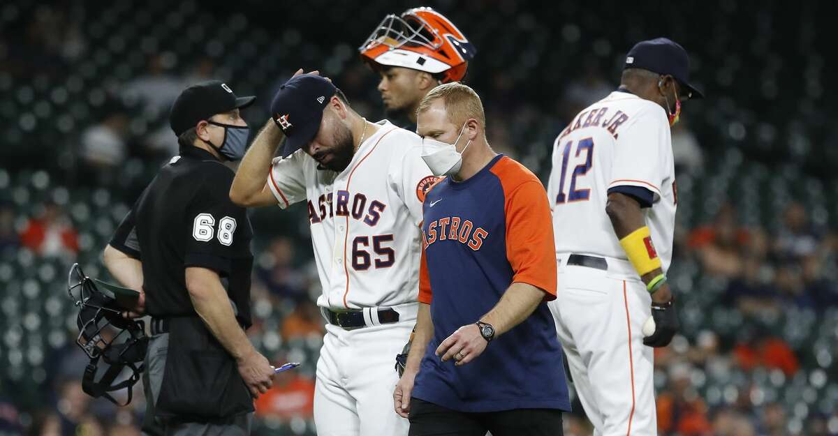 Houston Astros starting pitcher Jose Urquidy is walked back to the dugout by a trainer after pitching coach Brent Strom noticed his fastball velocity was down from 94 earlier in the game to 89-90 during the fourth inning of an MLB baseball game at Minute Maid Park, Wednesday, May 12, 2021, in Houston.