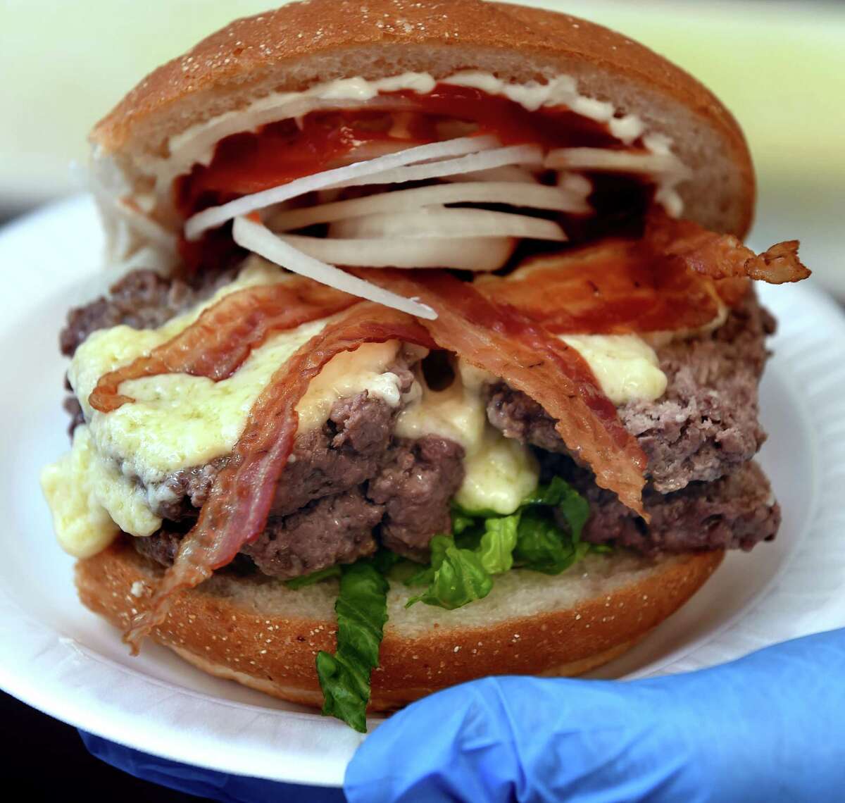 General manager Dylan McNulty shows off a double cheeseburger with melted aged Wisconsin sharp cheddar cheese at LaMay's Steamed Cheeseburgers in Meriden on May 14, 2021.