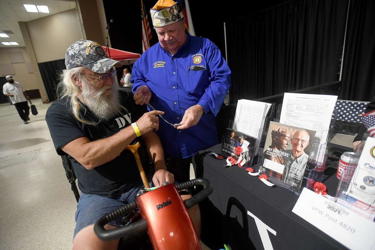VFW Post 4820 member Jim Rose hands a specialty Navy dog tag for veteran Robert Sanford during Southeast Texas Stand Down 2021 in Port Arthur Friday. Numerouse veterans organizations as well as other health and community action services filled the Bob A. Bowers Civic Center for the event, which aims to connect veterans and the homeless with needed resources. A fall event will be held in Beaumont. Photo made Friday, May 14, 2021 Kim Brent/The Enterprise