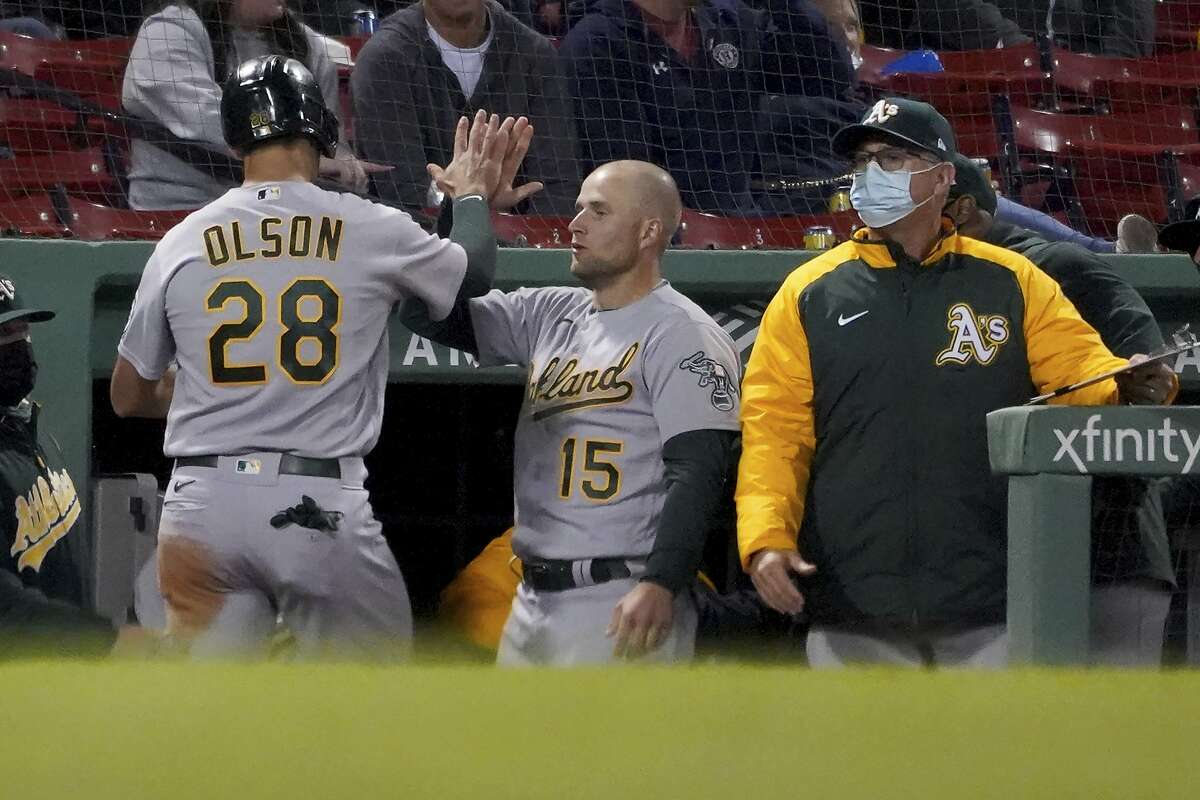 Oakland Athletics' Matt Olson (28) is congratulated at the dugout by Seth Brown (15) after scoring on a hit by Matt Chapman during the seventh inning of a baseball game against the Boston Red Sox, Tuesday, May 11, 2021, in Boston. (AP Photo/Mary Schwalm)