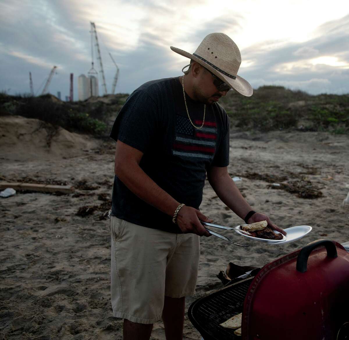 Jesus Chavez plates his food while his daughter Brianna Chavez wander behind him. The family came to Boca Chica beach to celebrate Brianna?•s 16th birthday. They were forced to wait on Highway 4, the only way into the beach, because SpaceX was moving equipment. Road closures from the space facility are common.