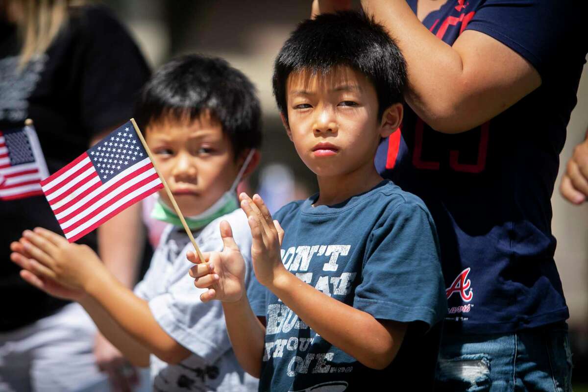 Brothers Lawrence, left, and Linus, center, clap during a “Together — We Are United” rally at the Sugar Land Town Square on Saturday, May 15, 2021. The event was hosted by several organizations to denounce violence in the Asian community.