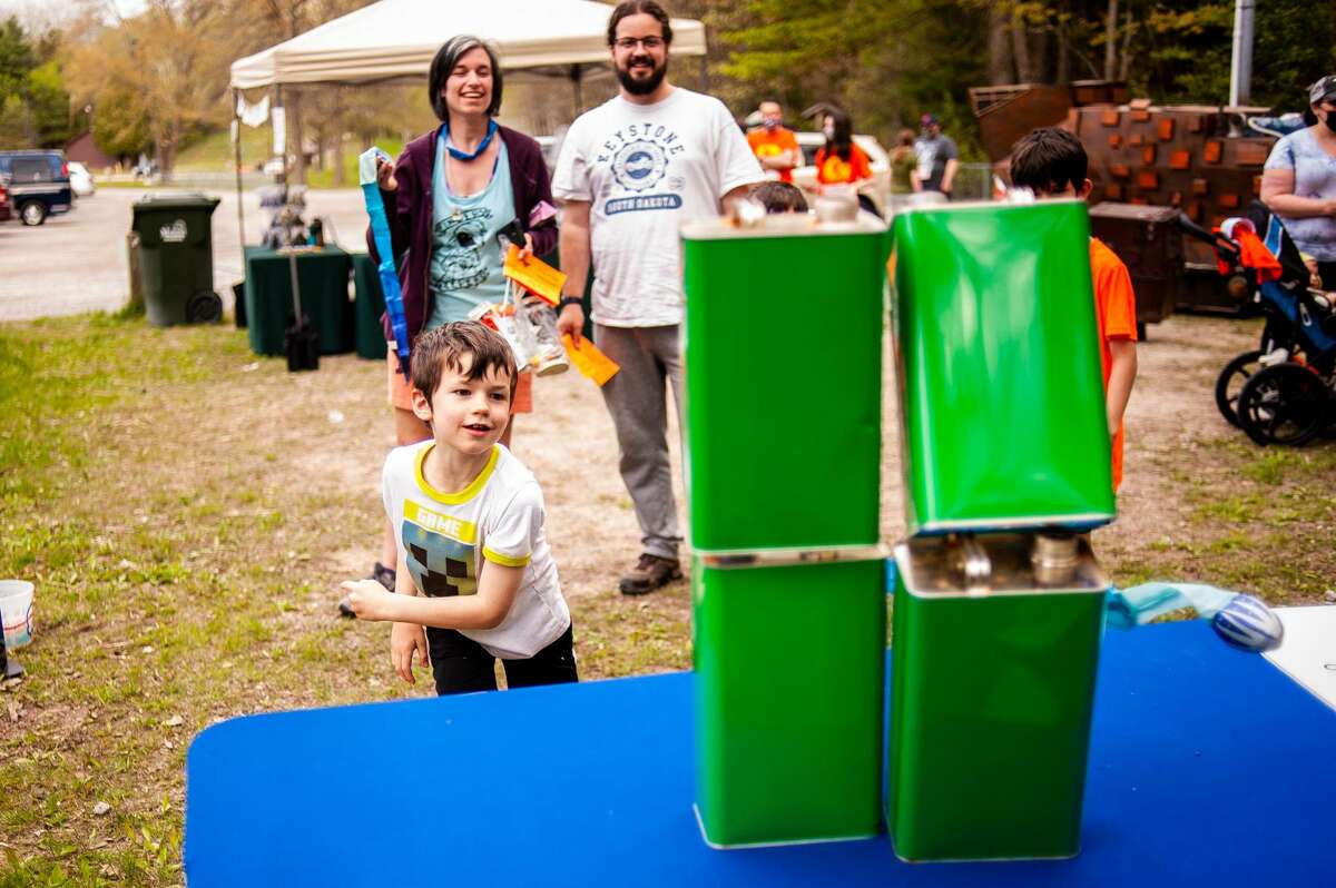 Ryan Frye (left), 7, knocks over cans at the Midland Recyclers 5K Fun Run/Walk event on May 15, 2021, at the Midland City Forest.