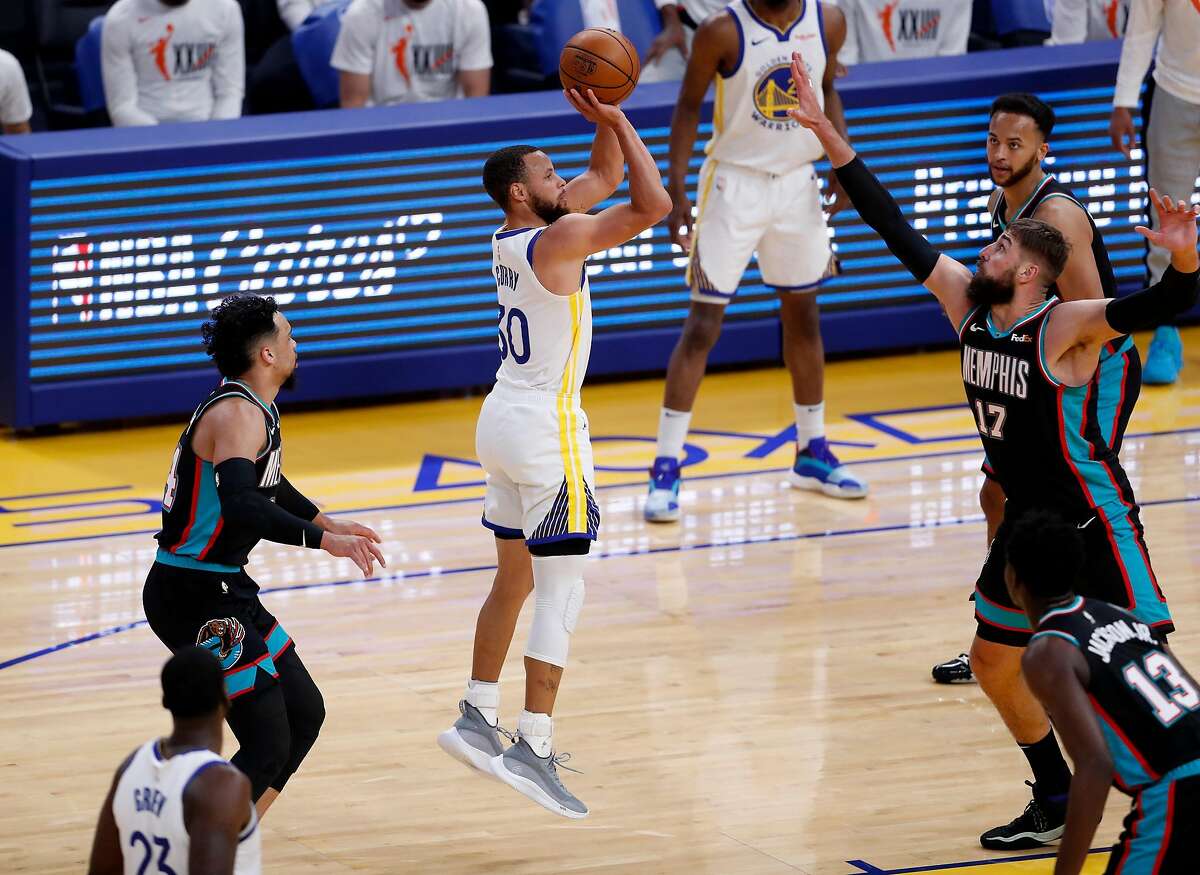 Golden State Warriors' Stephen Curry shoots between Memphis Grizzlies' Jonas Valanciunas and Dillon Brooks in first quarter during a game at Chase Center in San Francisco, Calif., on Sunday, May 16, 2021.
